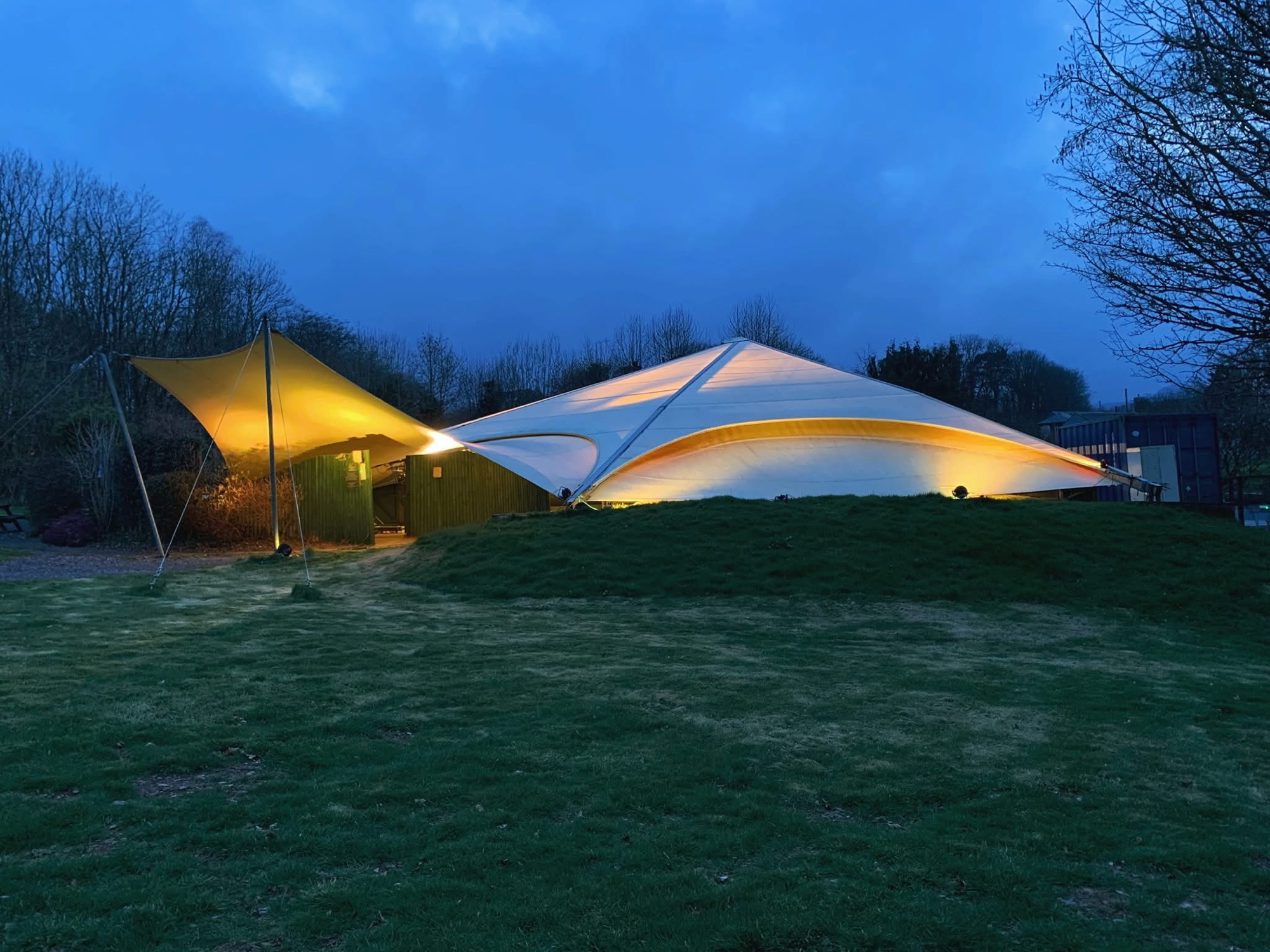 The tensile fabric canopy structure lit up at dusk
